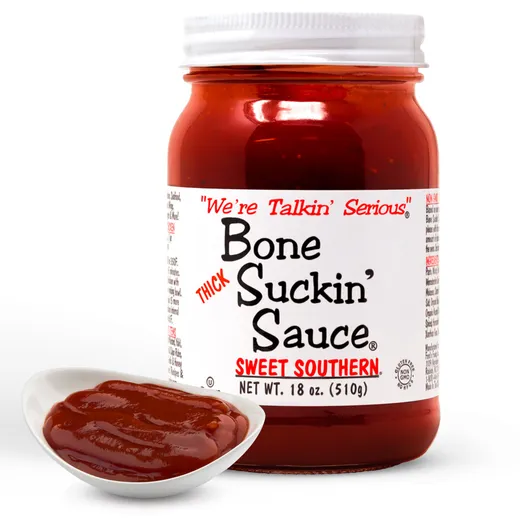 A jar of Bone Suckin' Sauce Sweet Southern next to a small white bowl of the sauce.