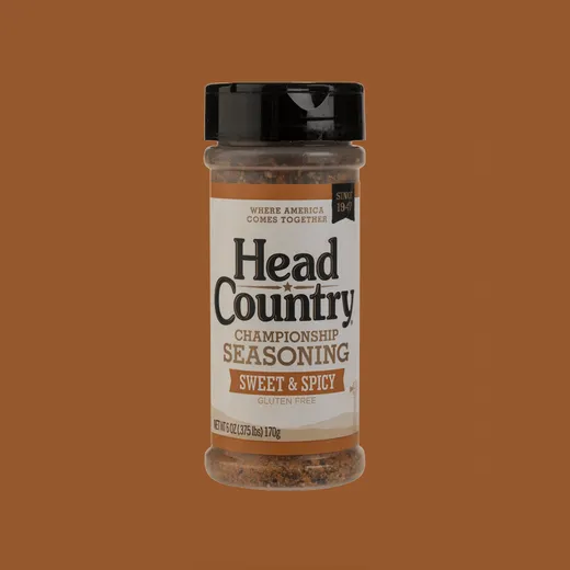 A container of Head Country championship seasoning standing against a plain brown background.