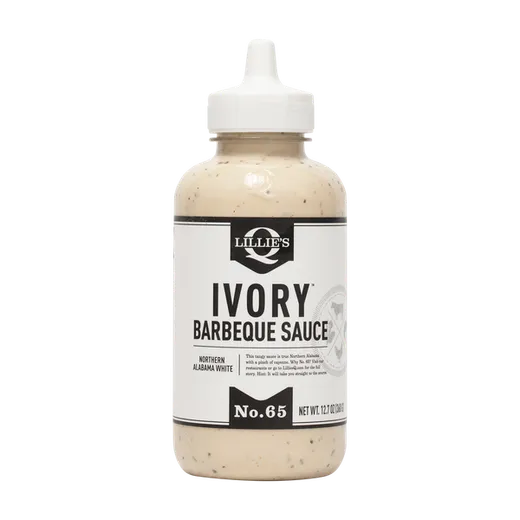 A full bottle of Lillie's Q Ivory Barbeque Sauce centered against a plain black background.