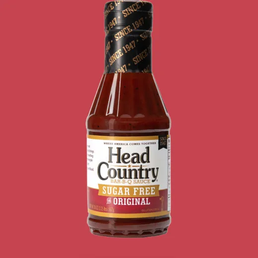 A bottle of Head Country Sugar Free Original Bar-B-Q sauce isolated on a red background.