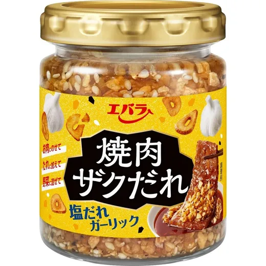A clear jar filled with a chunky garlic and sesame condiment against a white background.