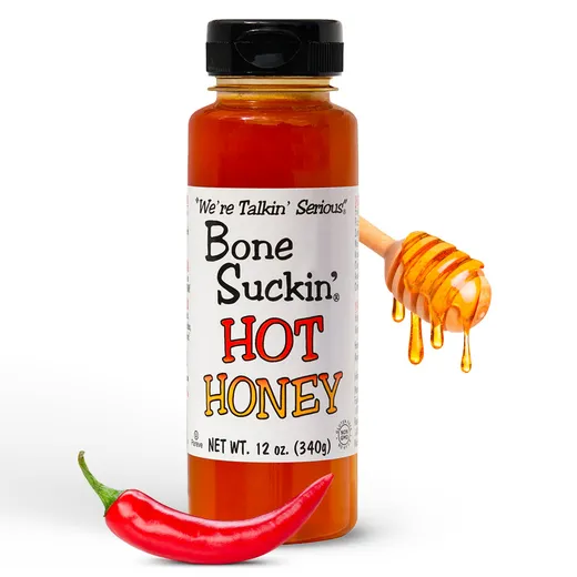 A bottle of Bone Suckin' Hot Honey with a honey dipper and red chili pepper against a white background.